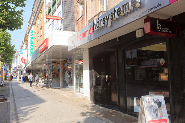 Geschäftsstraße mit Schaufenstern von Hörgeräteakustiker, Deichmann und Verbraucherzentrale.